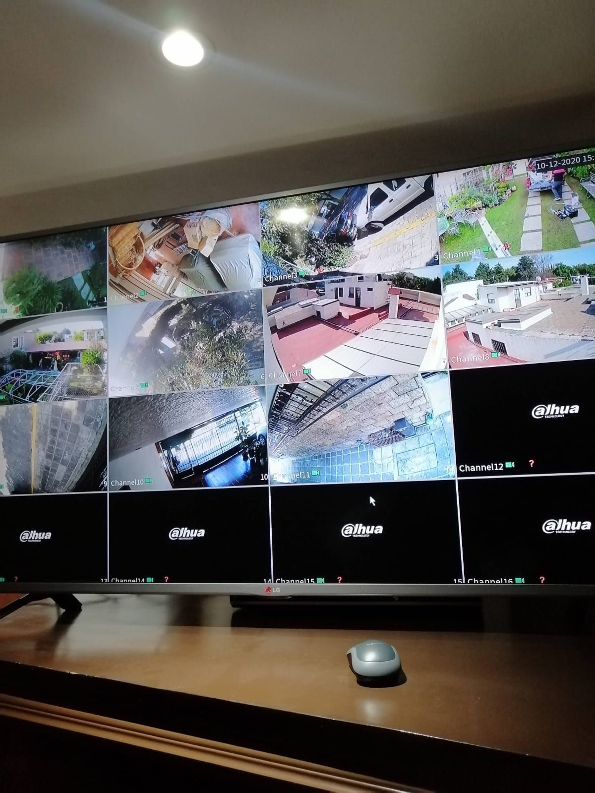 Monitores de seguridad que muestran múltiples vistas de cámaras, en un escritorio de madera con un mouse.