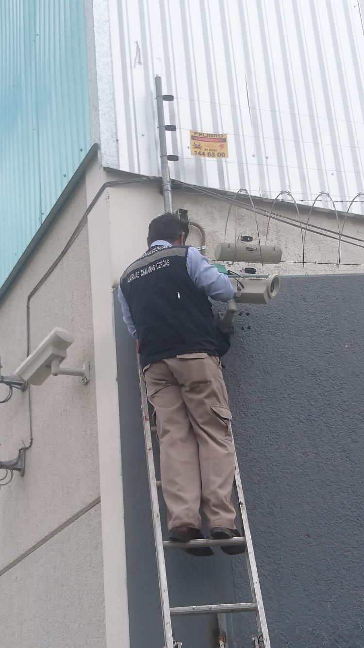 Una persona en una escalera cerca del techo de un edificio, parece estar trabajando en algo.