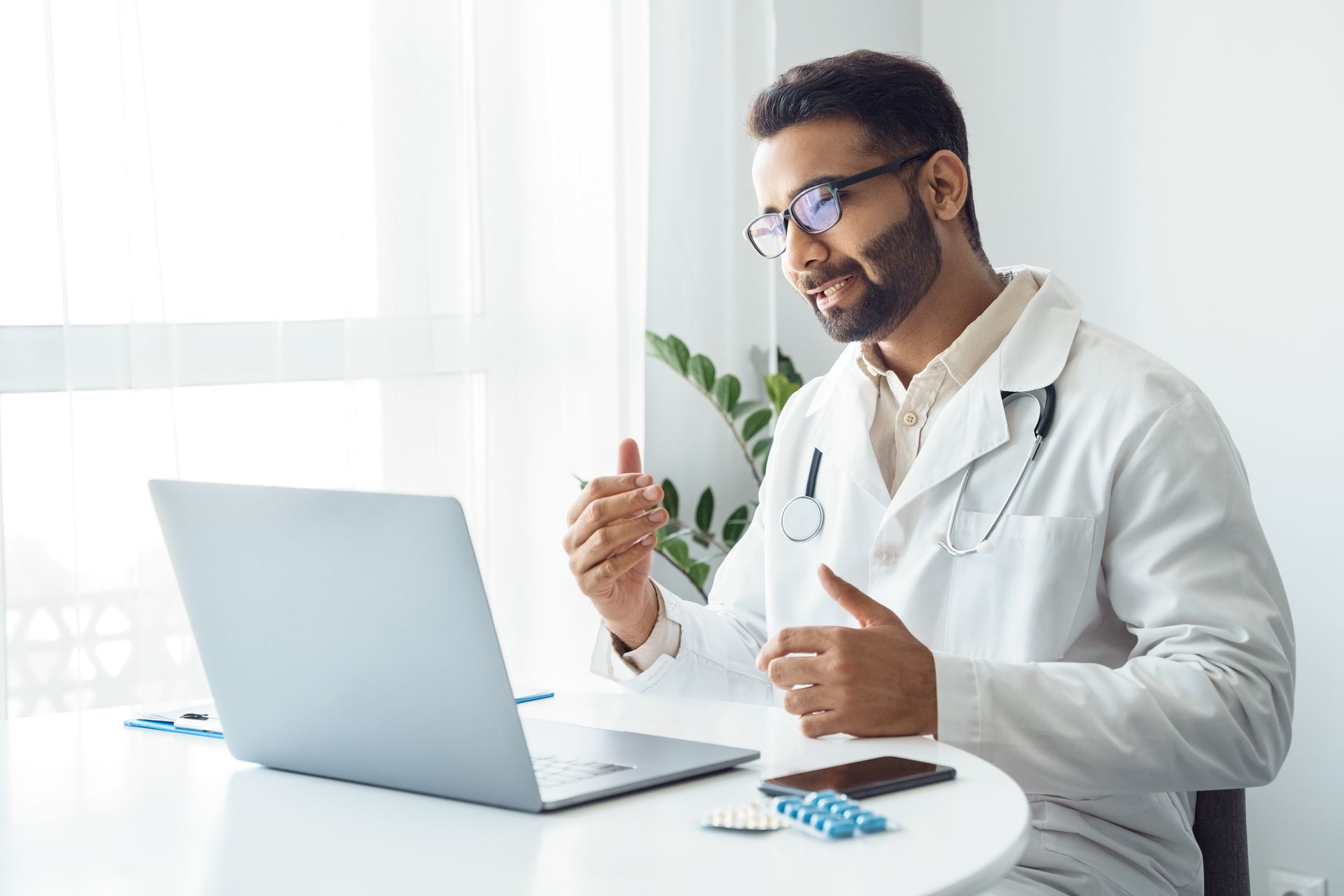 A doctor is sitting at a desk in front of a laptop computer.