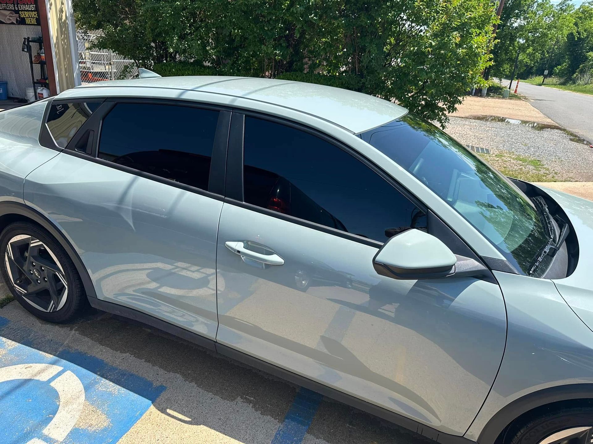 A silver car is parked in a handicapped parking spot.