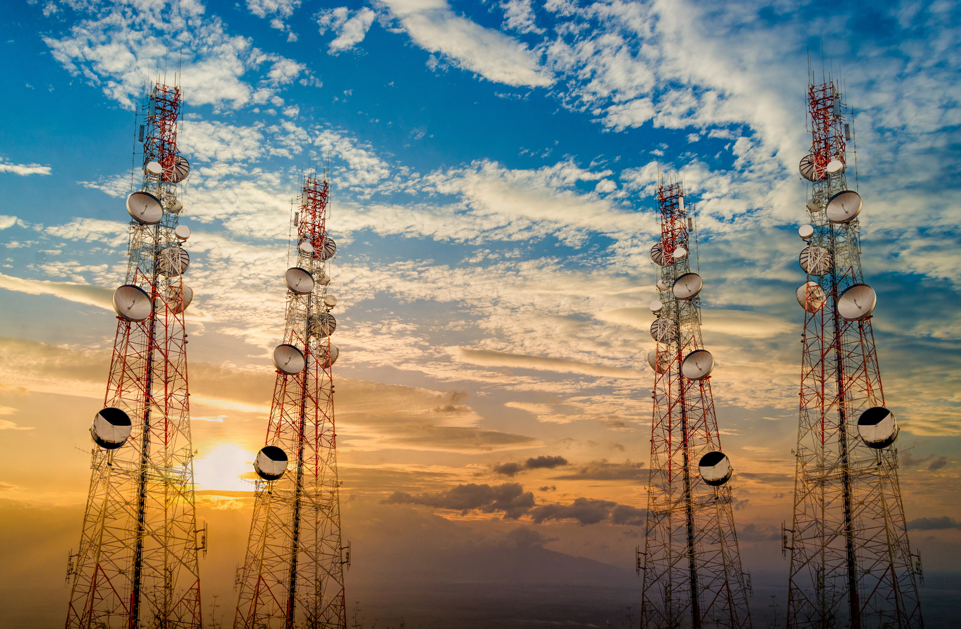 A row of telephone towers against a sunset sky.