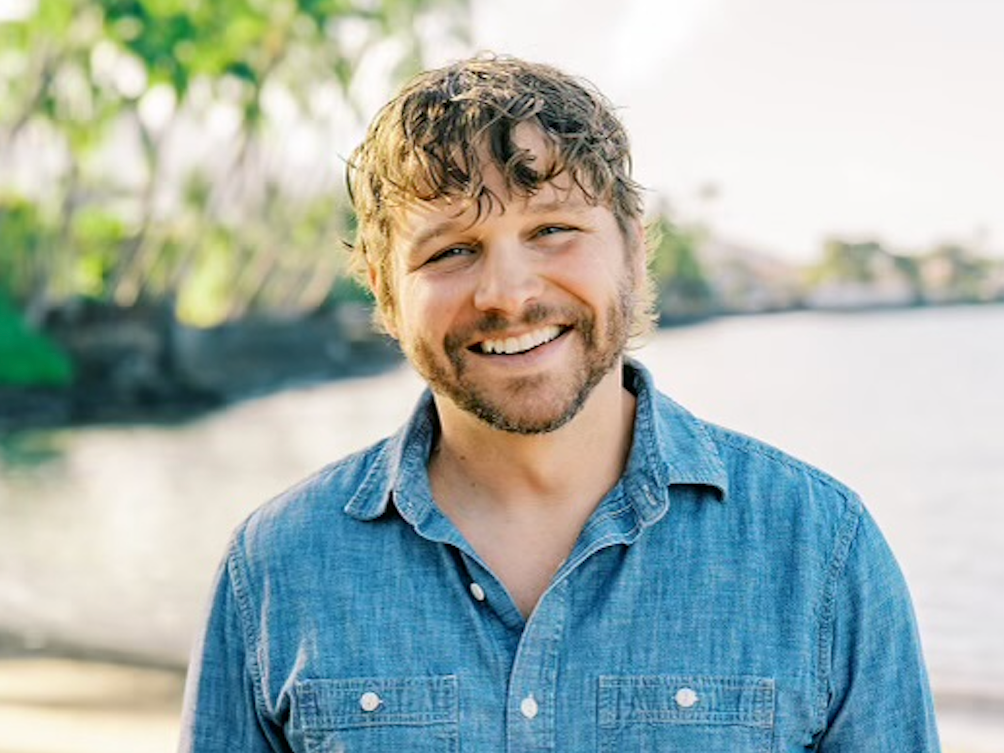 A man with a beard and a blue shirt is smiling for the camera.