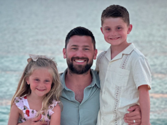 A man and two children are posing for a picture on the beach.