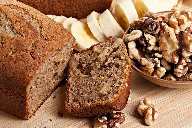 Banana bread with walnuts and banana slices on a wooden surface.