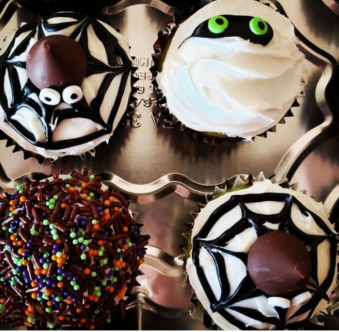 Halloween cupcakes: spiderweb, mummy, and sprinkle-covered cupcakes in a baking tray.