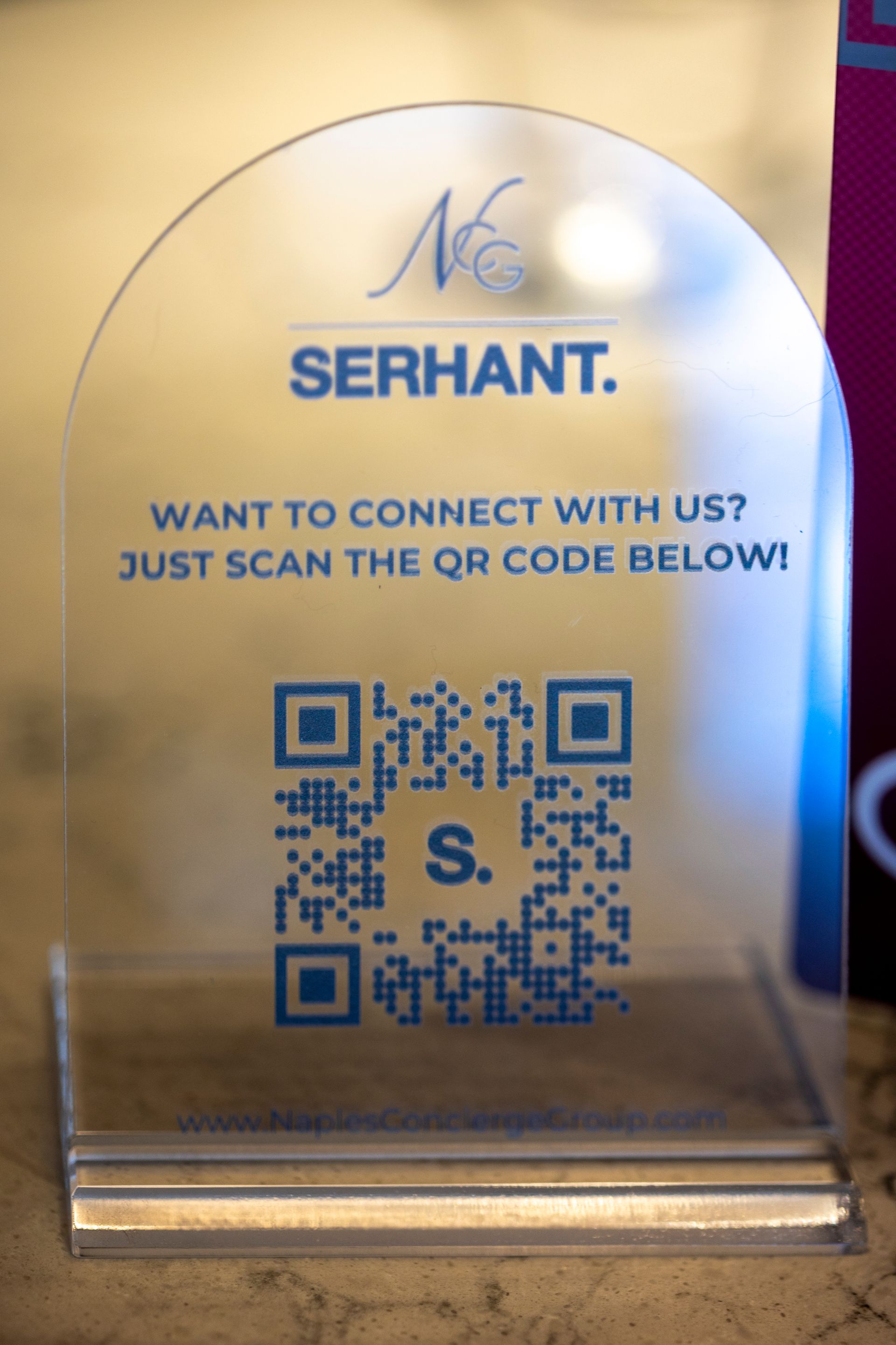 Clear acrylic sign with QR code for Serhant, inviting connection by scanning the code.
