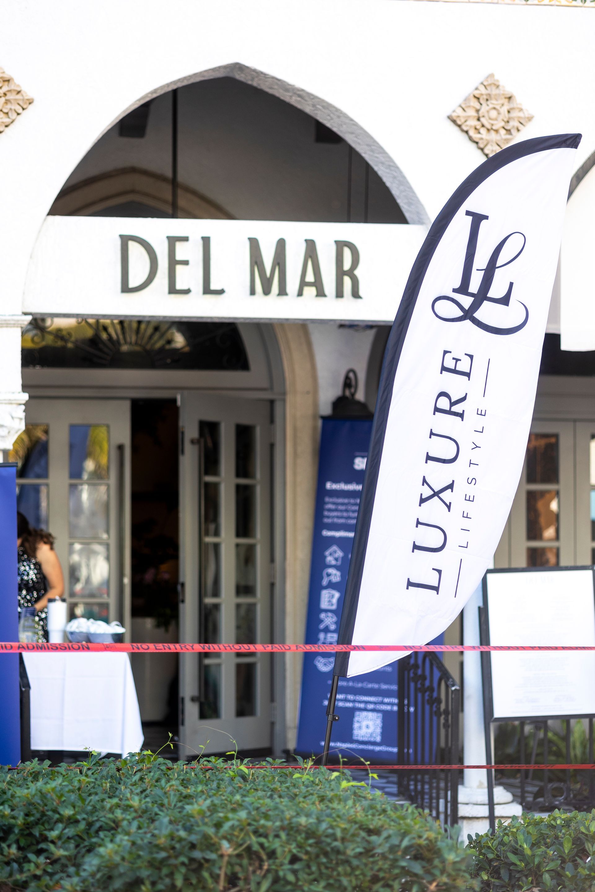 Entrance to Del Mar restaurant with a Luxure flag and a blue sign.