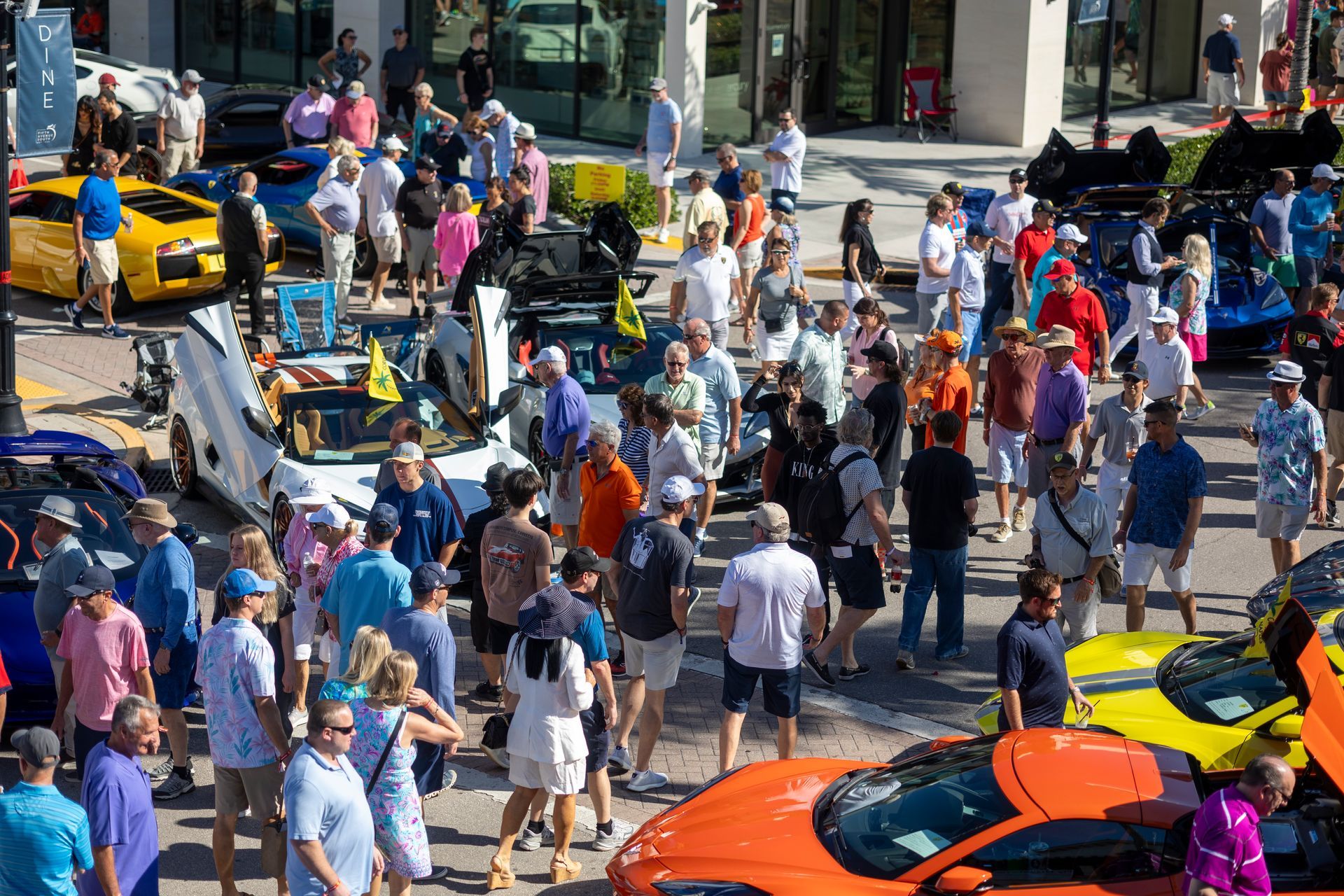 Crowd viewing colorful sports cars at an outdoor car show.