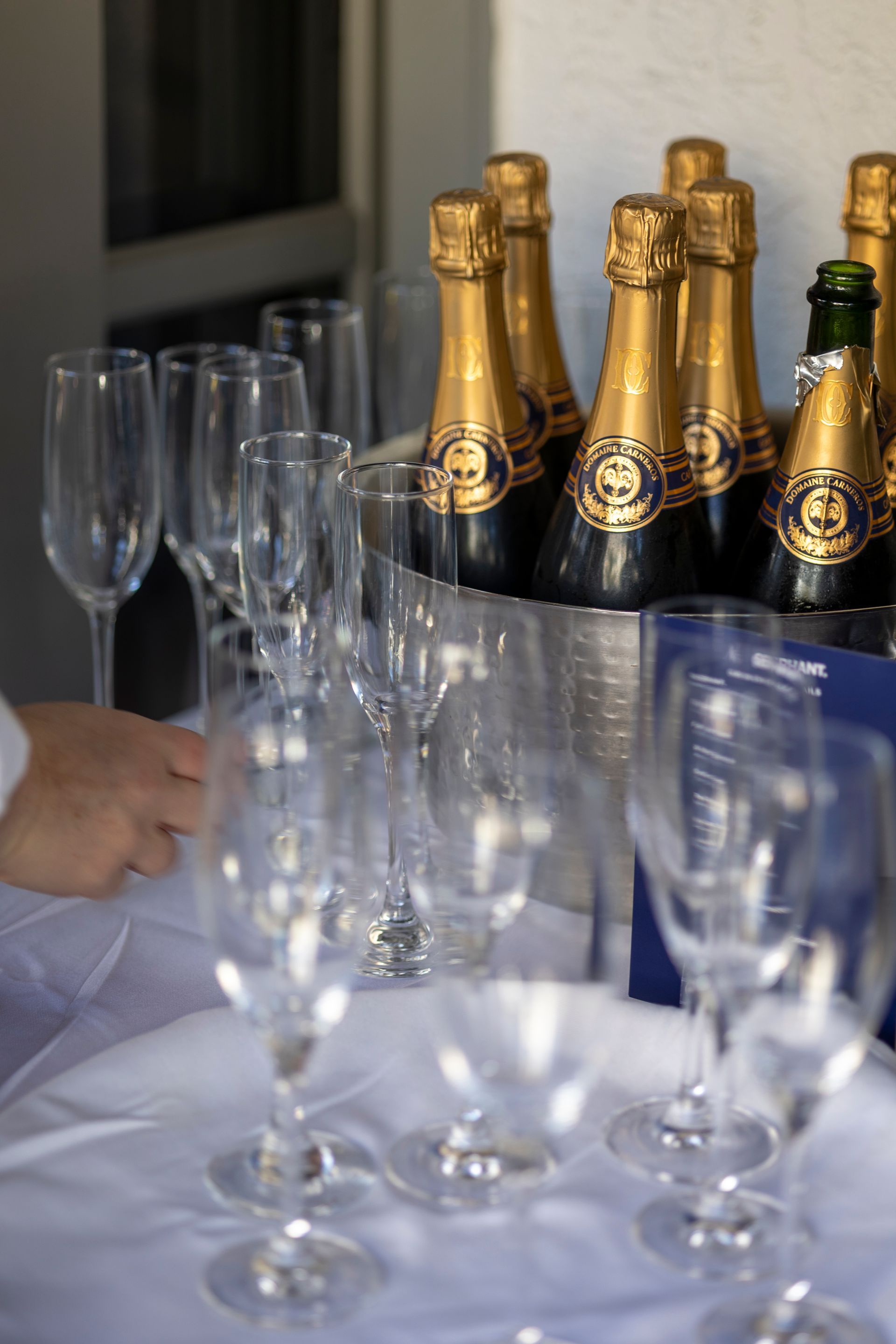 Champagne bottles in a metal ice bucket, champagne flutes on a white tray.