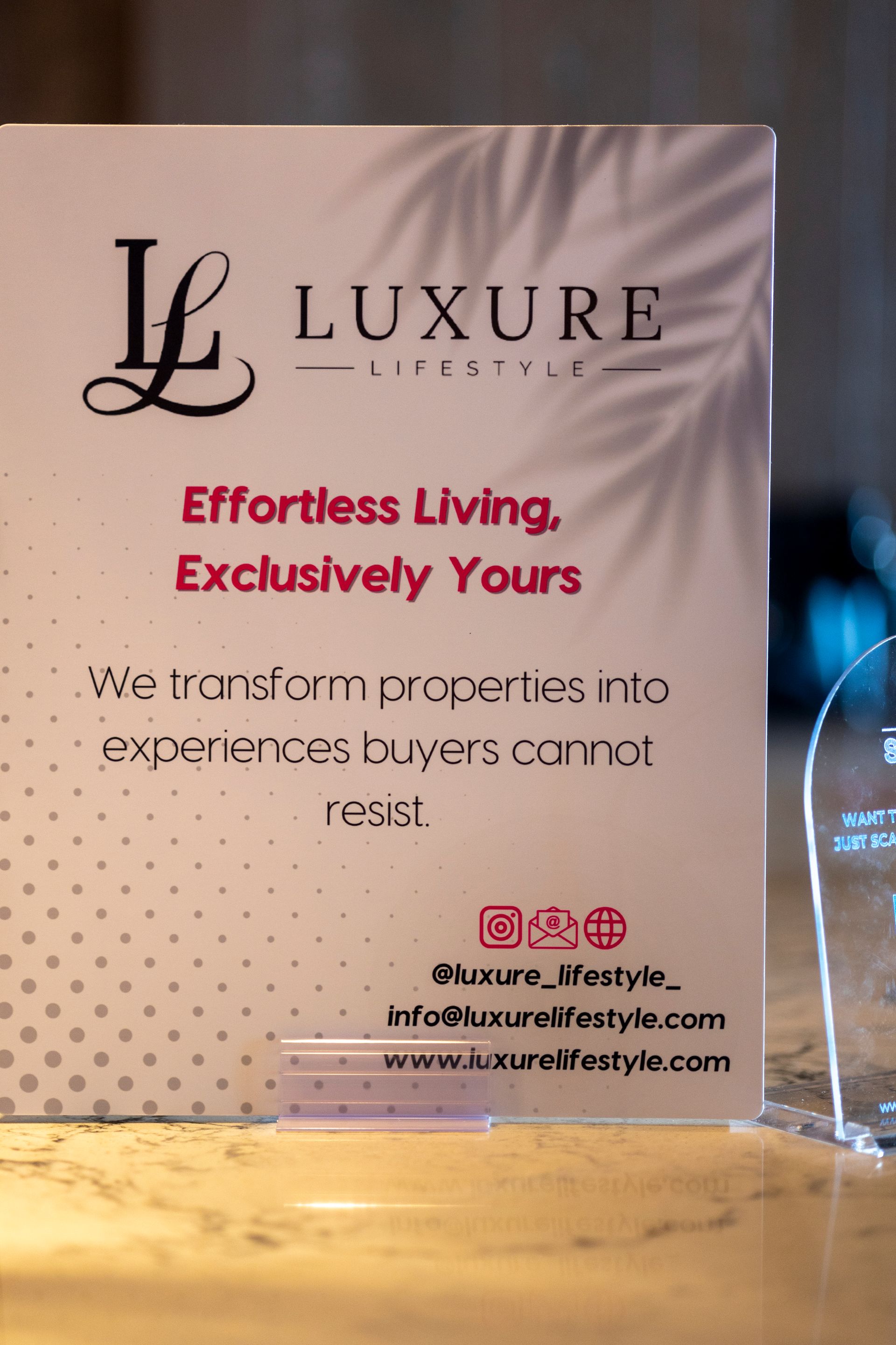 Luxure Lifestyle card with logo, tagline, contact info, on a light surface.
