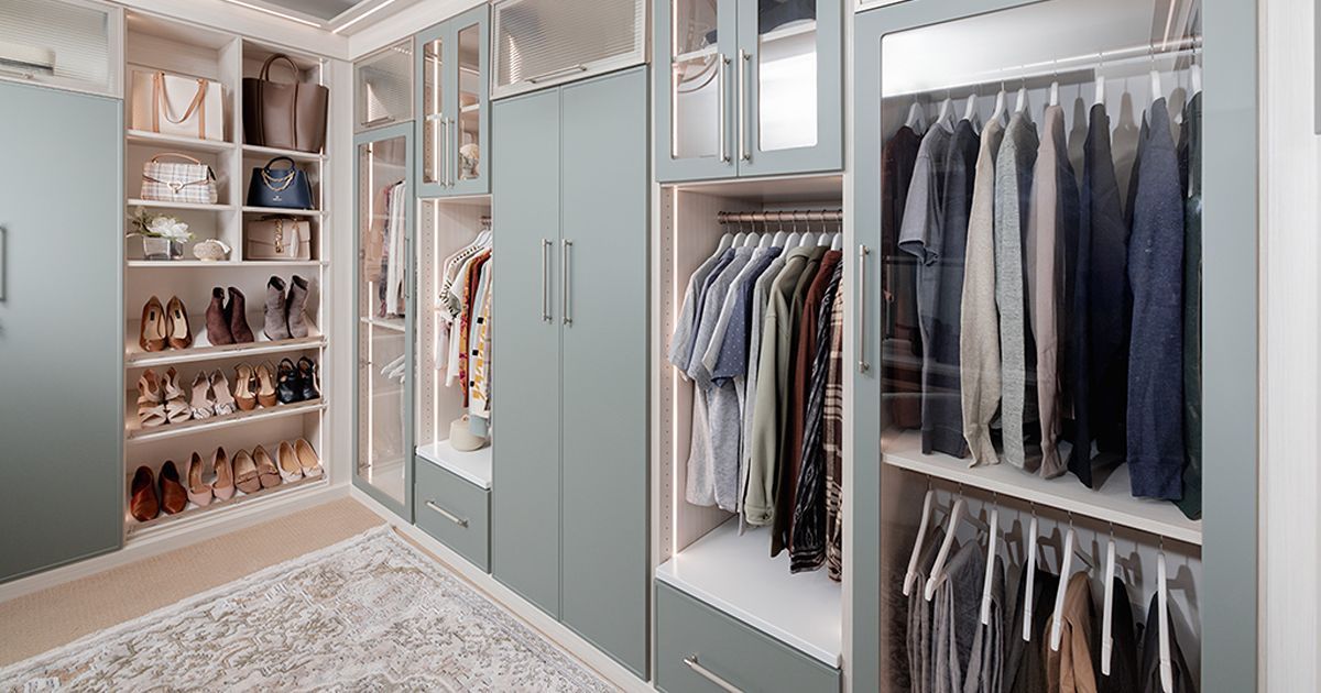 Walk-in closet with pale blue cabinets, shelving for shoes and purses, and hanging clothes.
