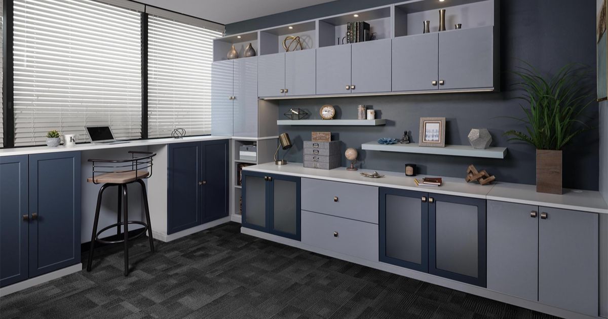 Office space with gray and blue built-in cabinets, desk, and large window with blinds.