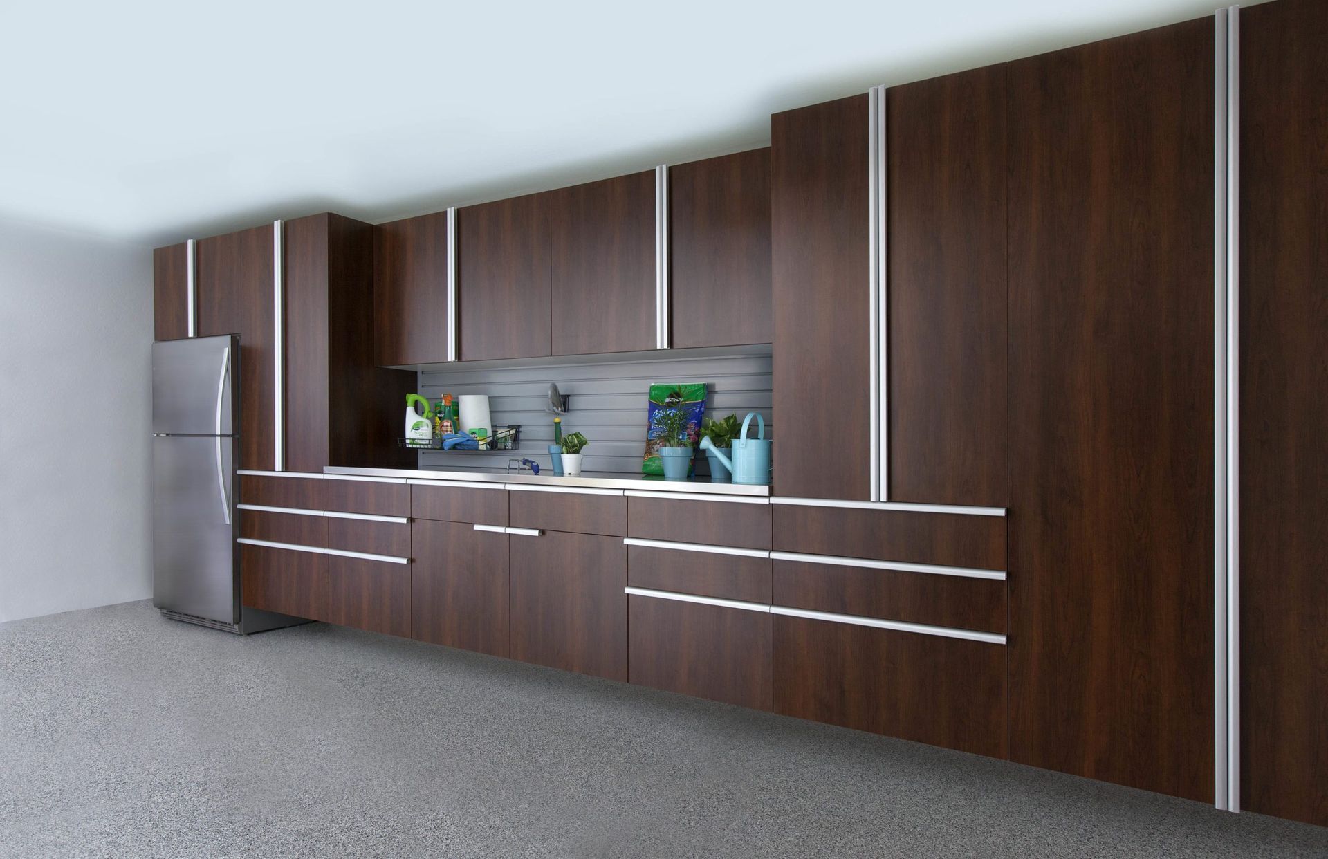 A modern kitchen wall with dark wood cabinets, silver hardware, and a stainless steel refrigerator on a speckled floor.