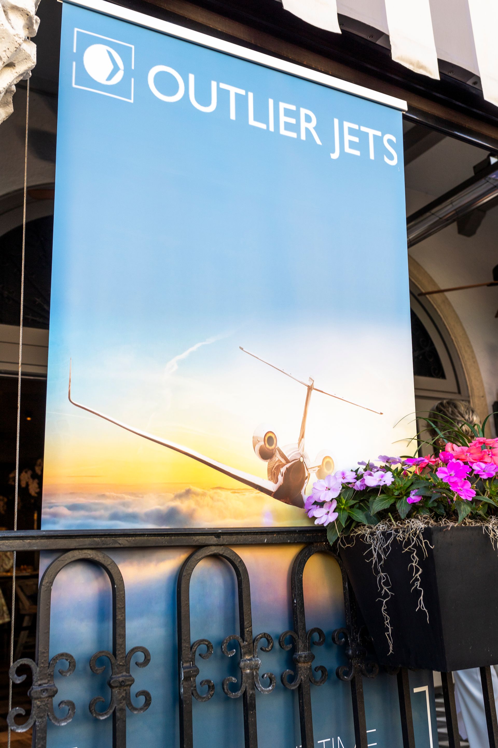Sign for Outlier Jets with a person mid-flight, blue sky background.
