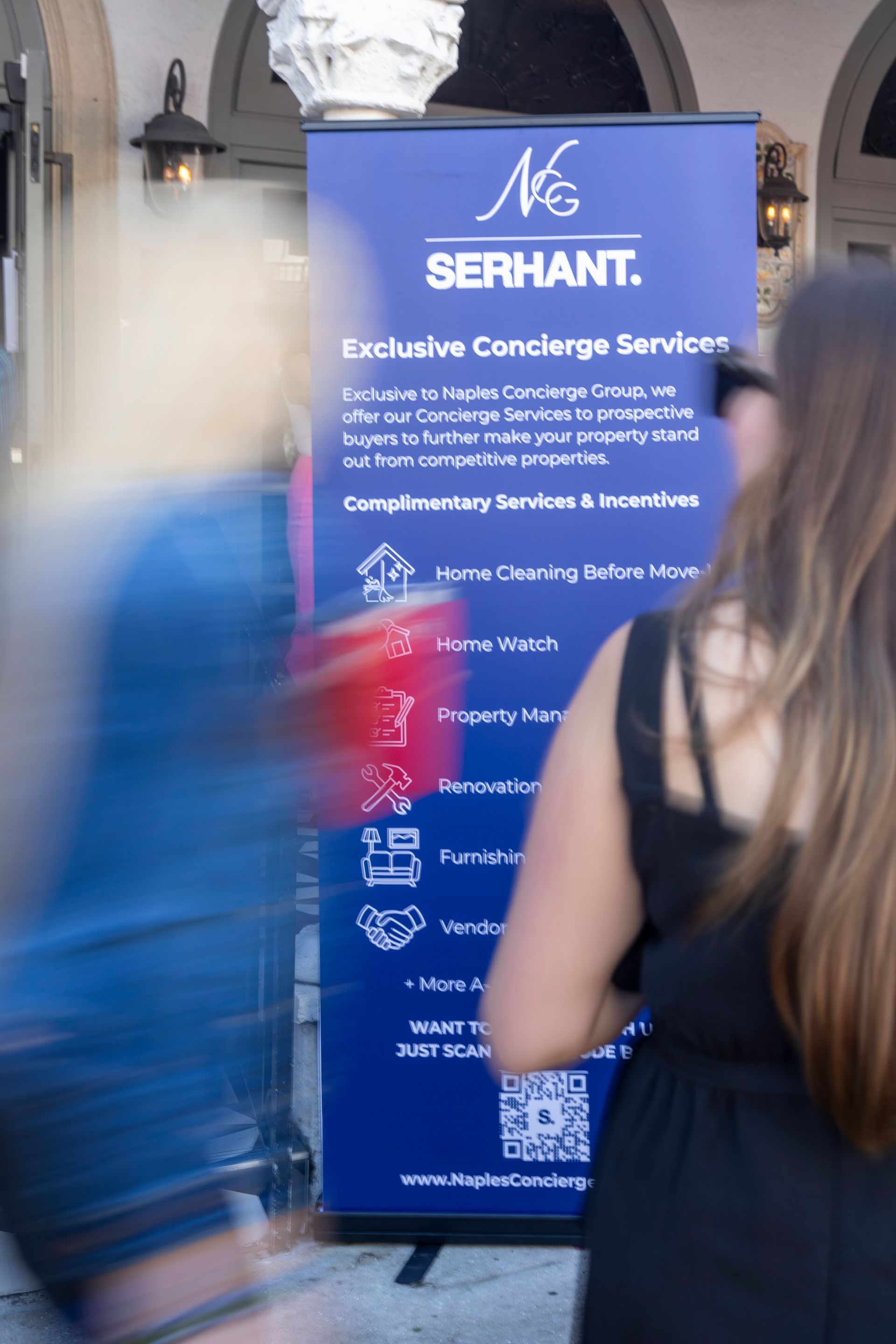 Blue banner advertising Serhant's exclusive concierge services, with blurred figures passing in front.
