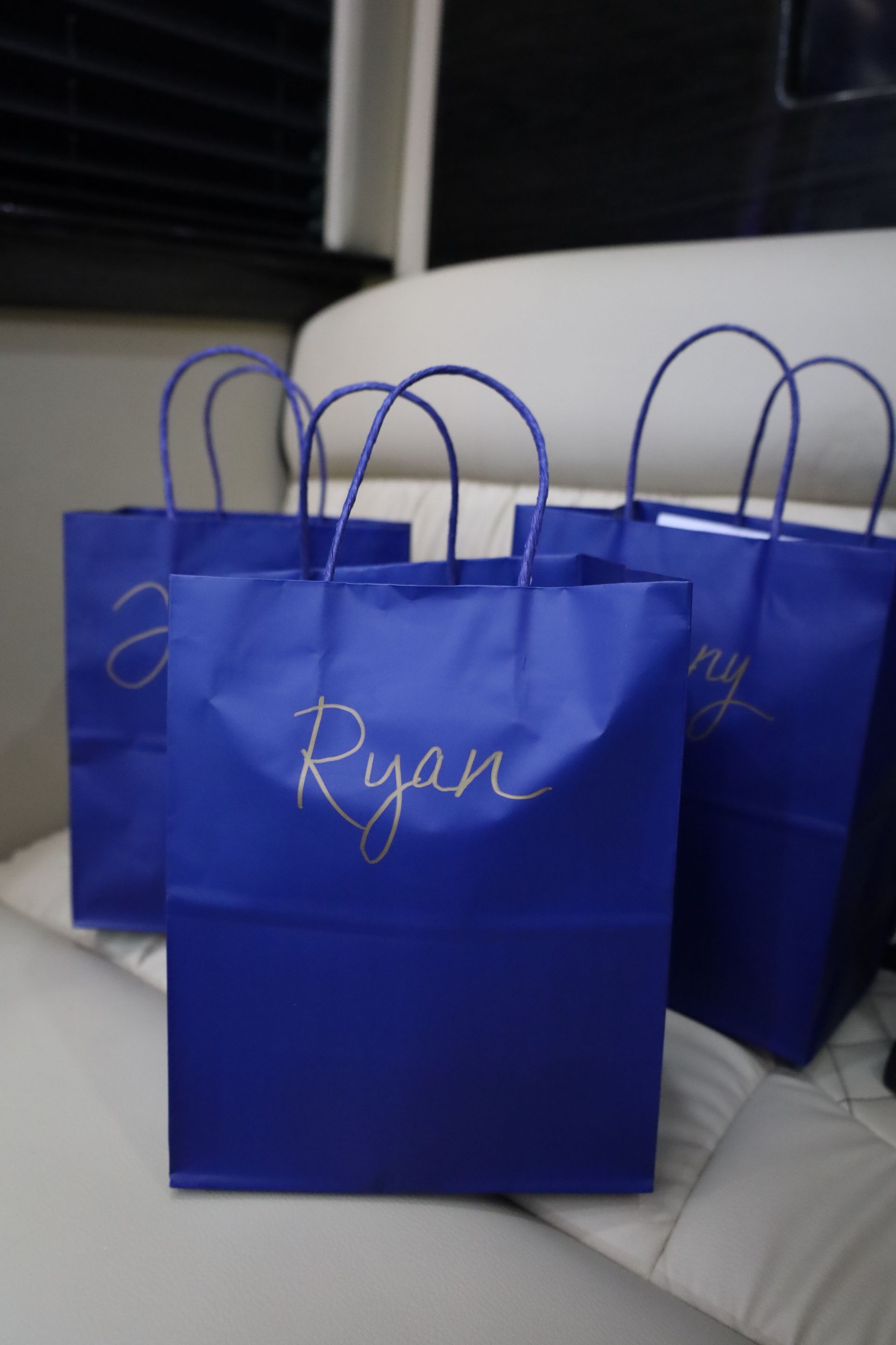 Three royal blue gift bags with gold lettering, 