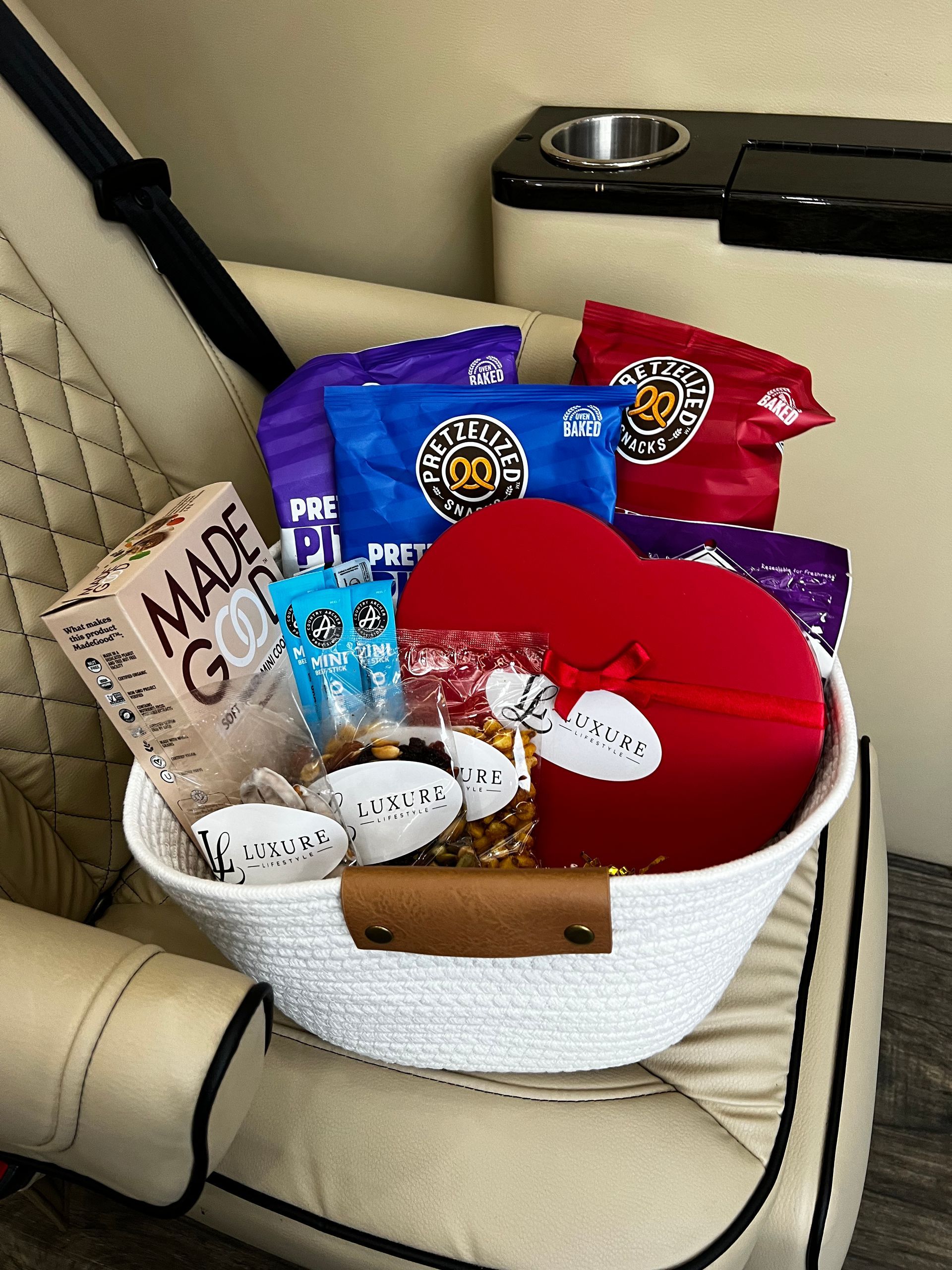 Basket with snacks and a heart-shaped box inside a vehicle seat.