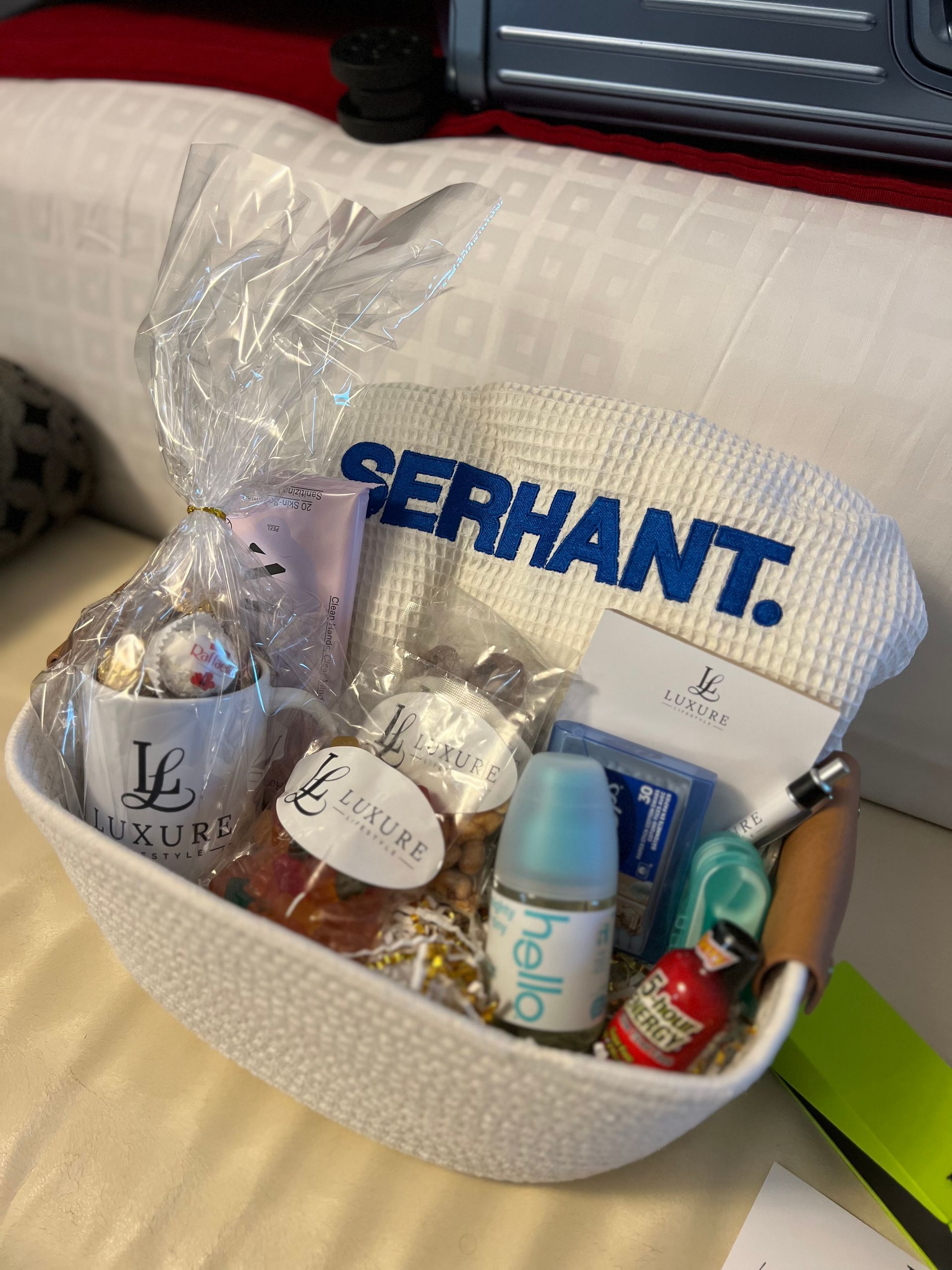 Gift basket with Serhant logo towel, mug, lotions, and snacks.