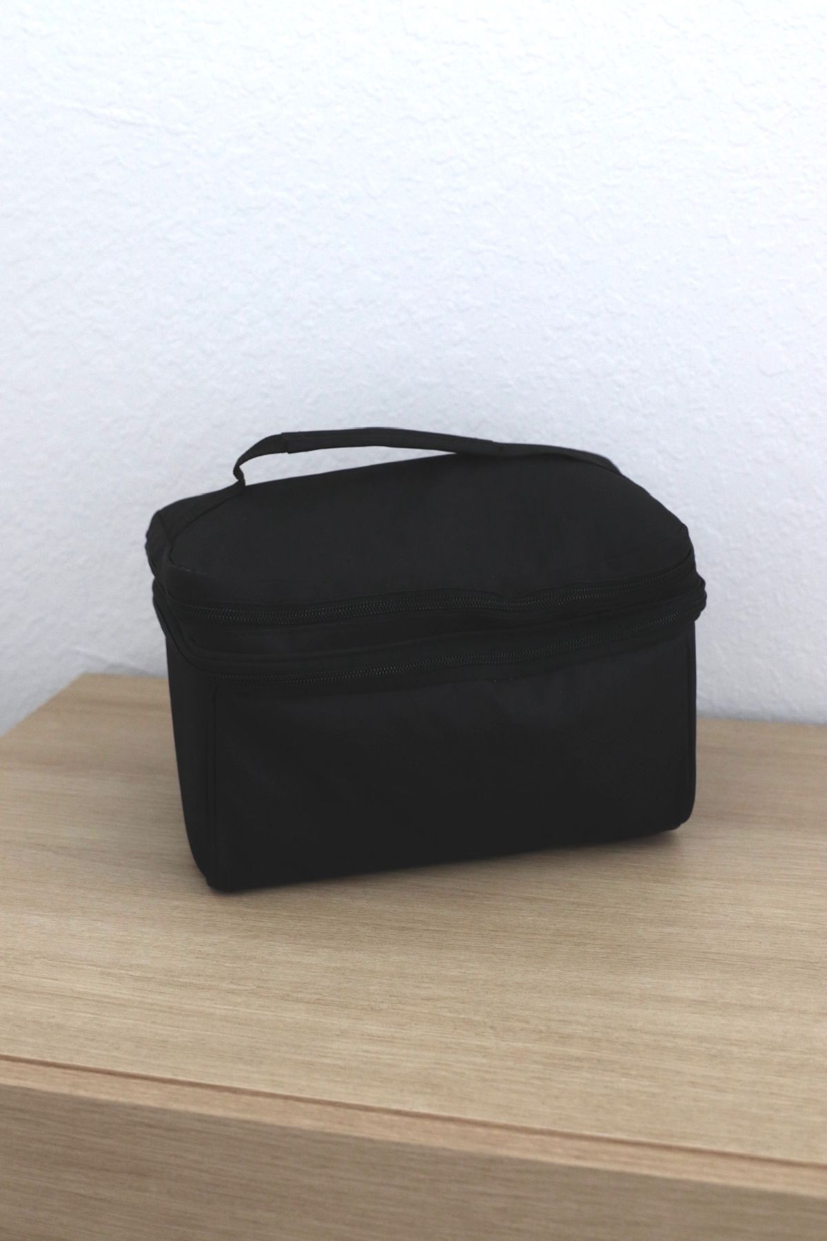 Black square case with a handle on a wooden surface.