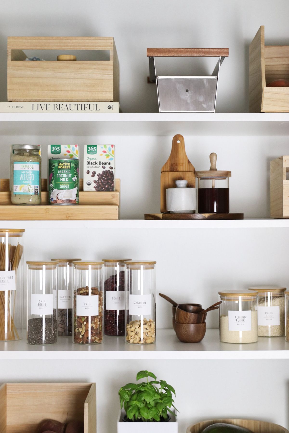 Shelves in a pantry, organized with jars, containers, and food items. White shelves, natural wood accents.