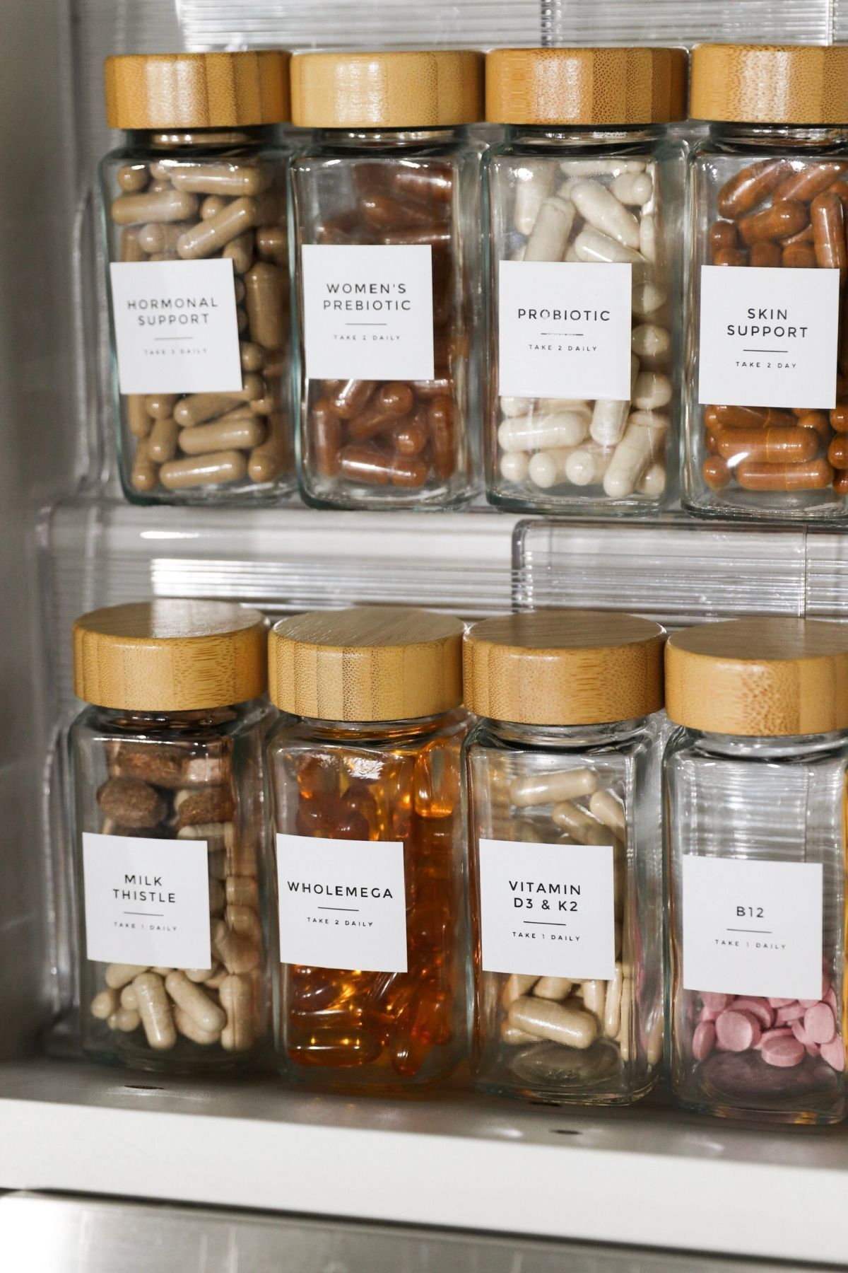 Glass jars with bamboo lids, labeled, containing various pills and capsules.
