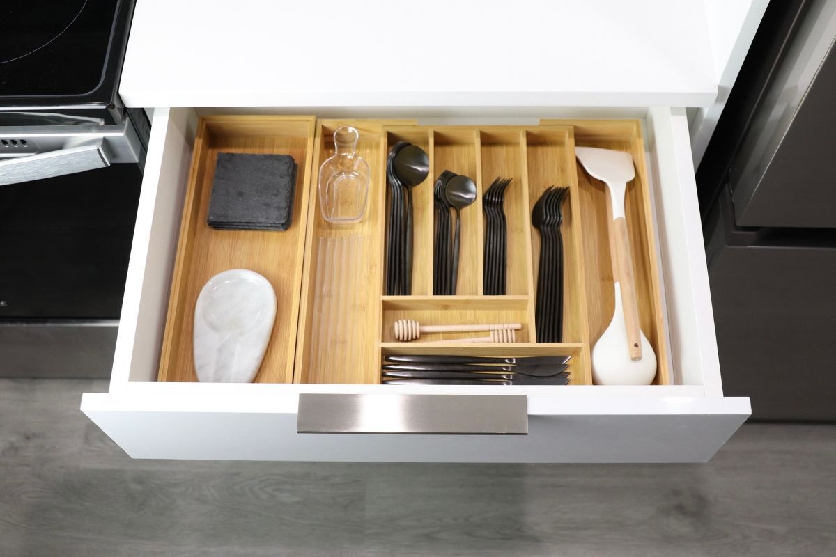 Open kitchen drawer with bamboo organizer holding utensils.
