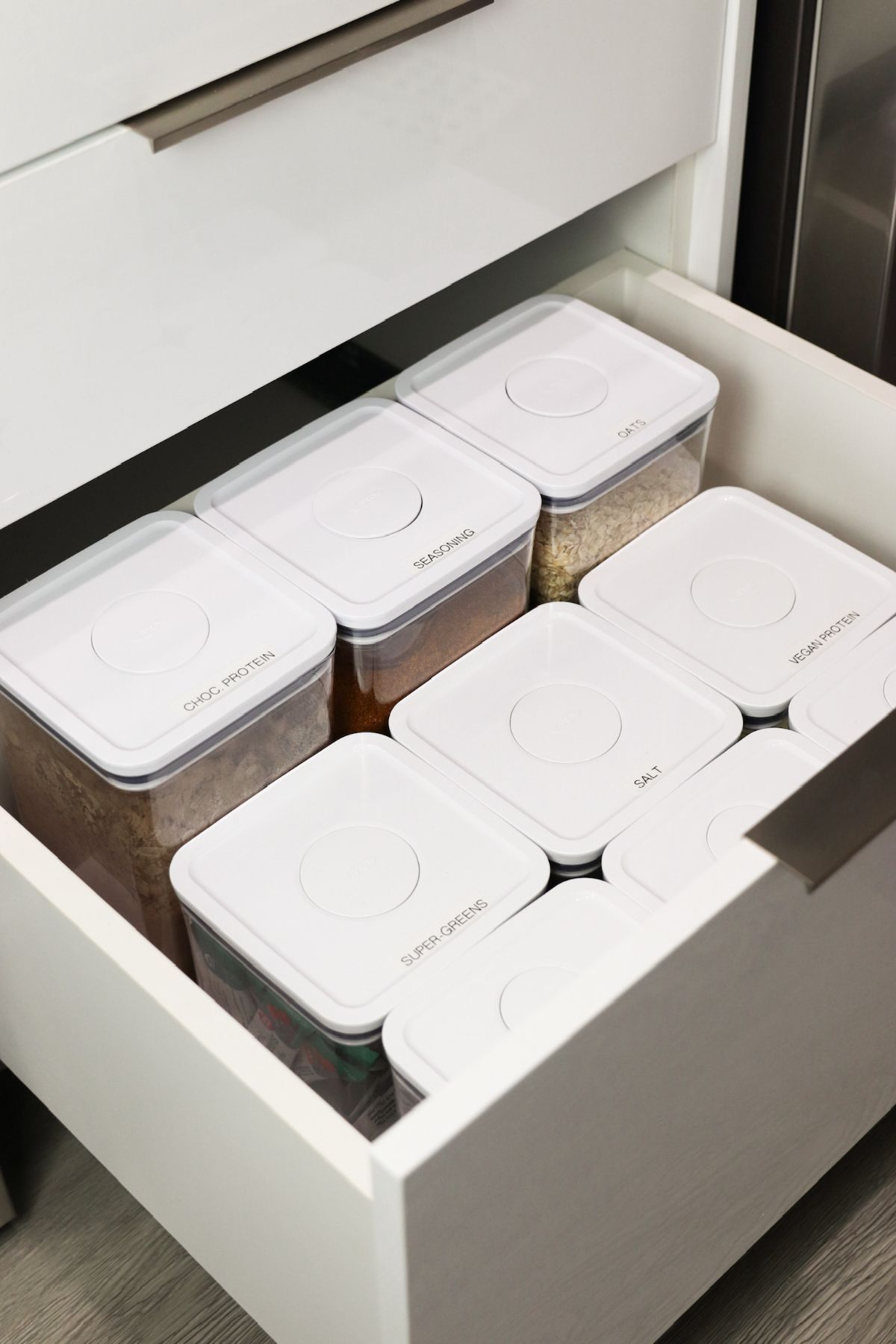 White kitchen drawer with organized food storage containers.