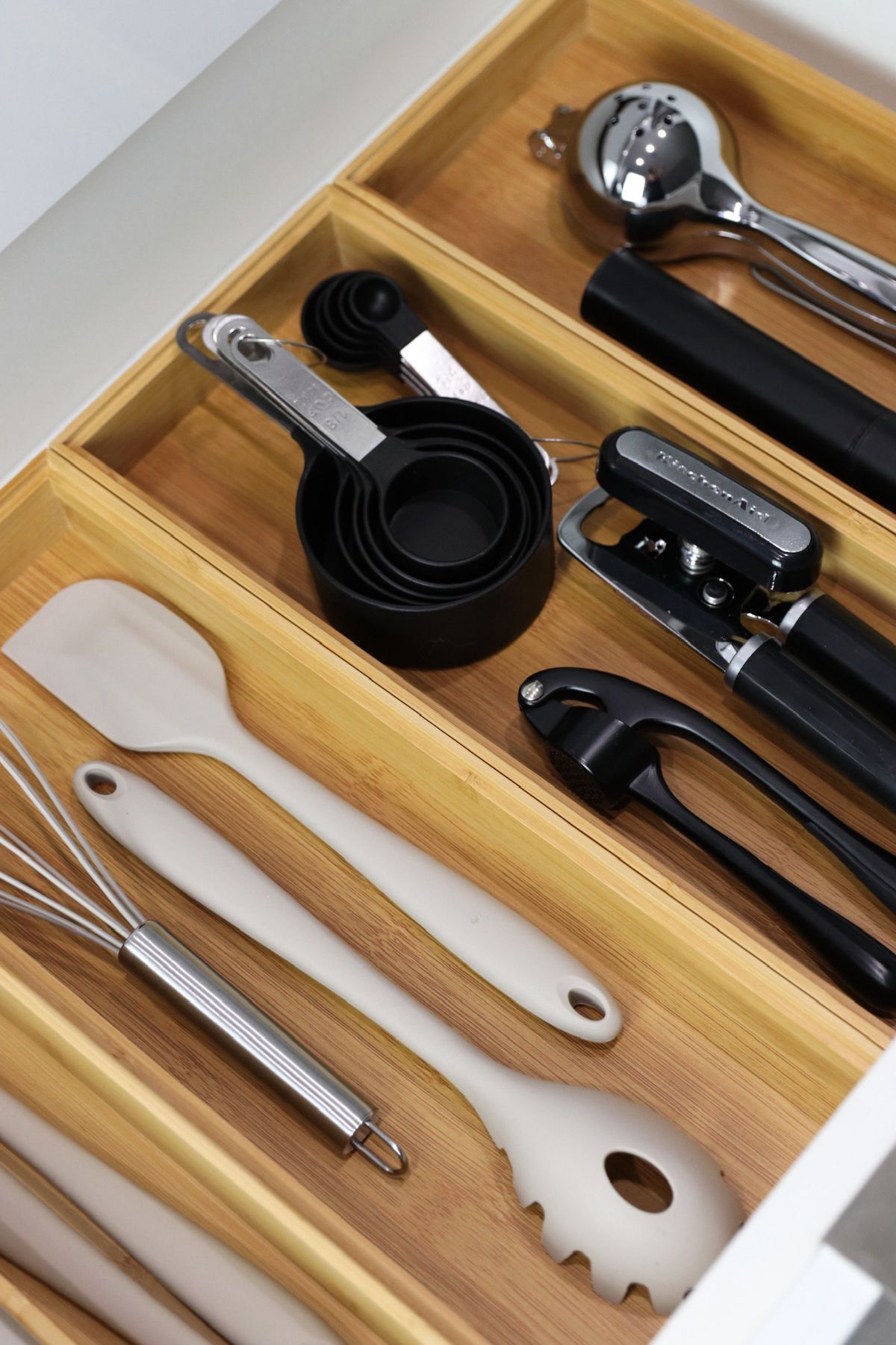 Kitchen drawer organized with utensils, including measuring cups, a whisk, and a spatula.
