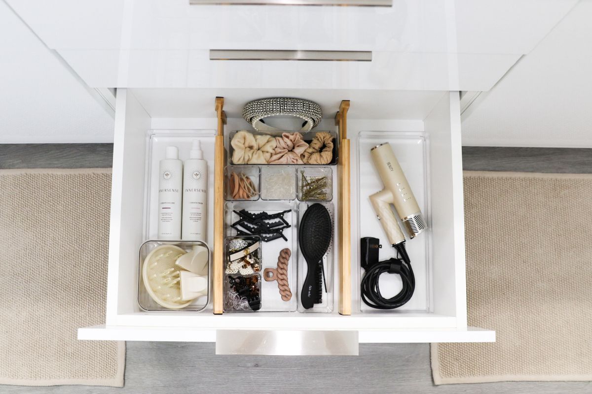Organized bathroom drawer with hair care products and accessories in clear containers.