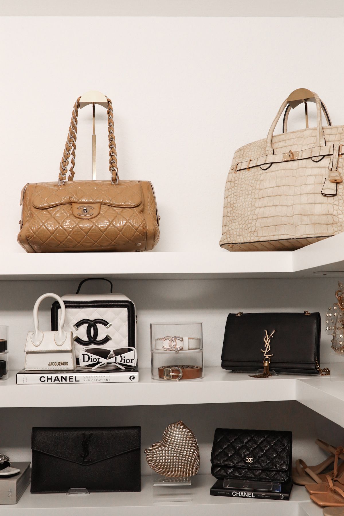 Designer handbags displayed on white shelves.