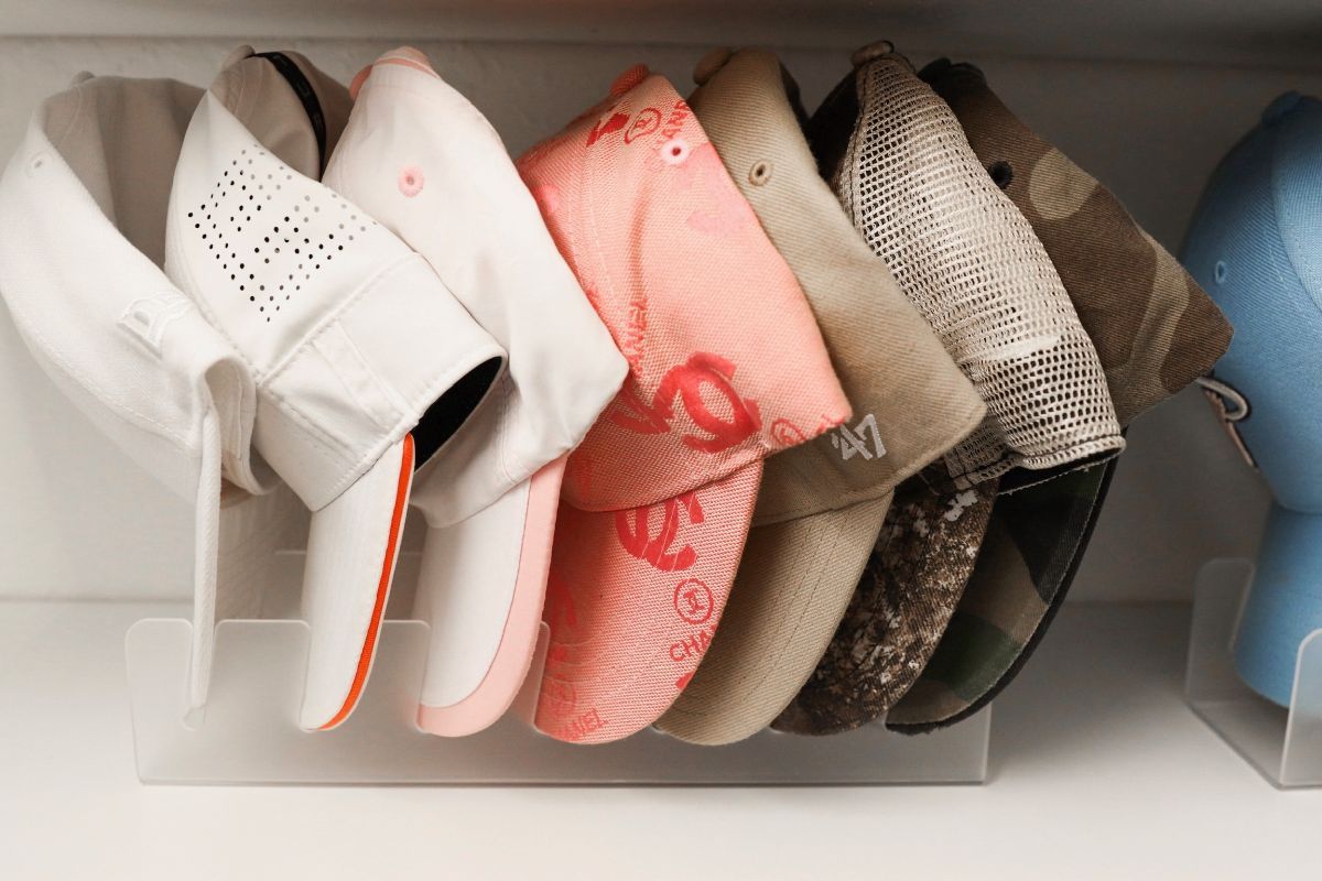 Caps in a clear plastic organizer, various colors and styles, inside a white closet.