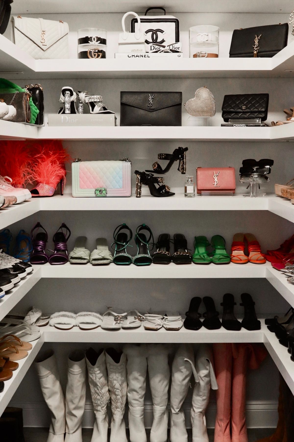 Closet with white shelves, displaying handbags, shoes, and accessories in a variety of colors and styles.