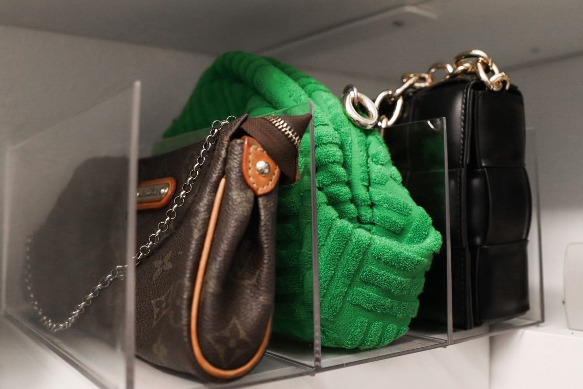 Three purses in a clear plastic organizer: brown, green, and black.