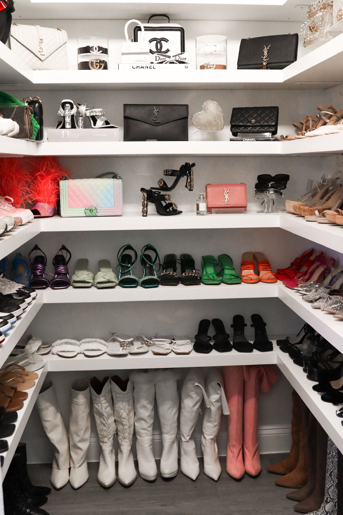 White closet filled with purses, shoes, and accessories on multiple shelves.