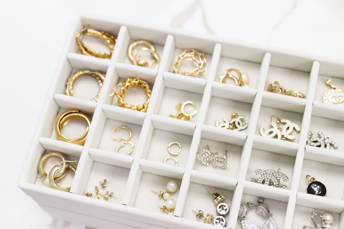 White jewelry box filled with various gold and silver earrings and rings.