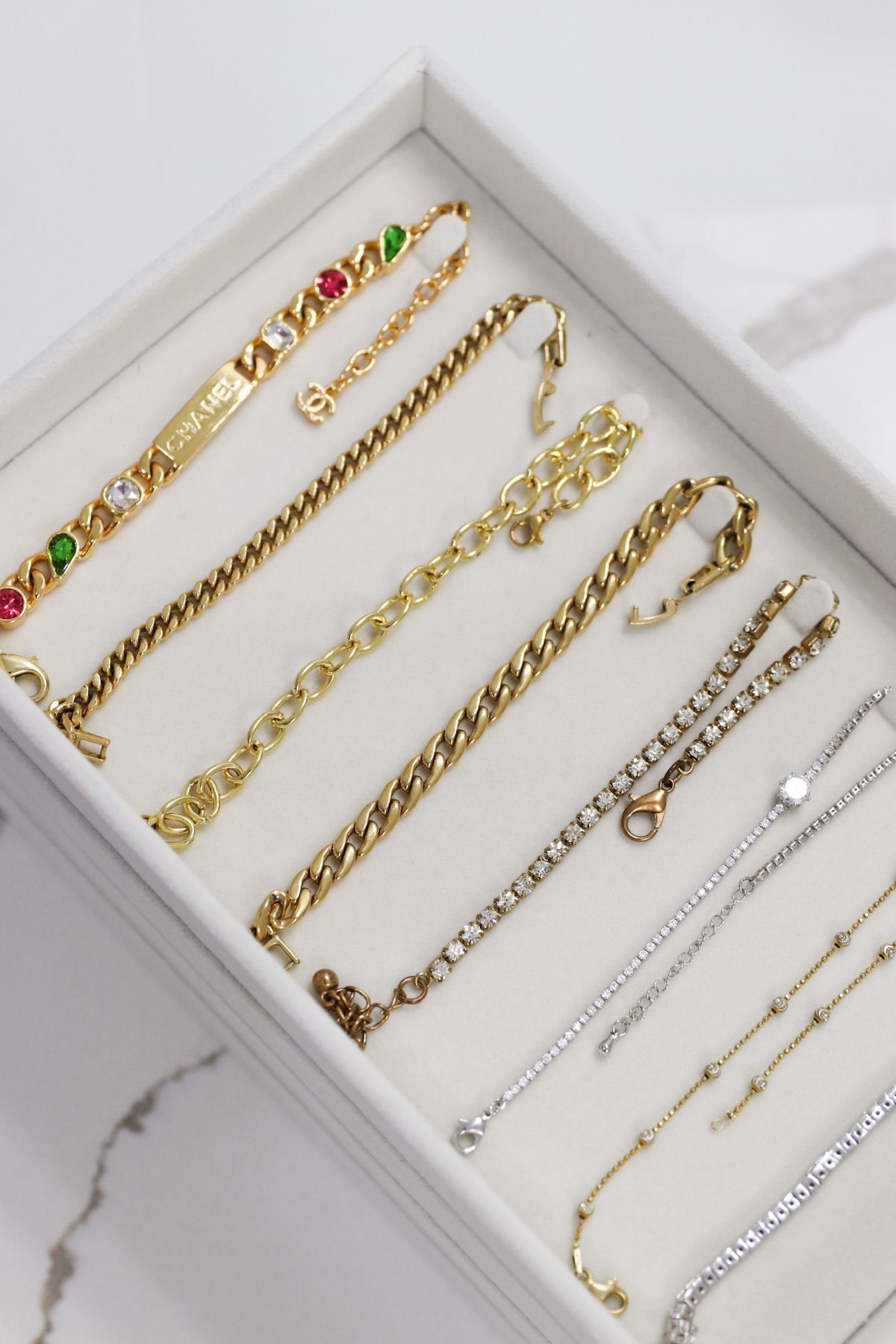 Jewelry display box with gold and silver bracelets, some with gemstones.