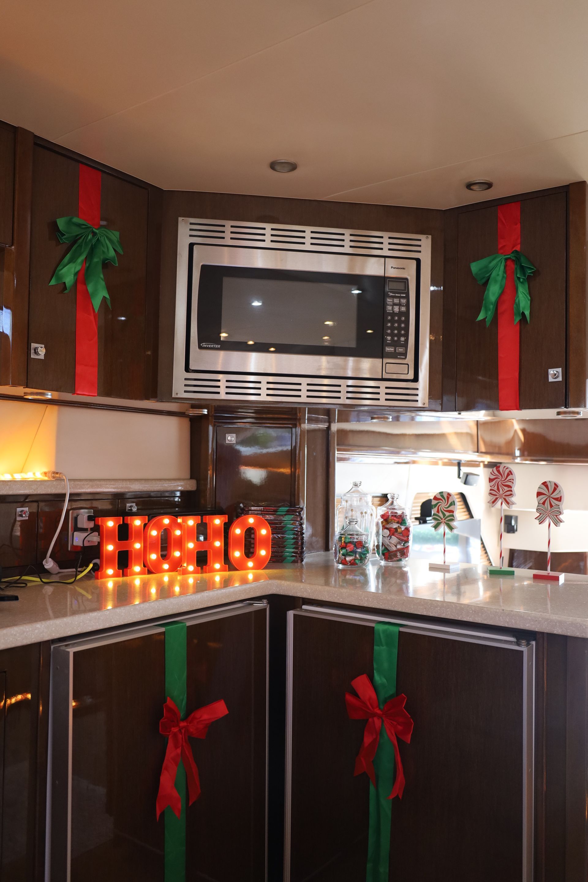 Christmas decorated kitchen with brown cabinets, red and green ribbons, microwave, and lit 