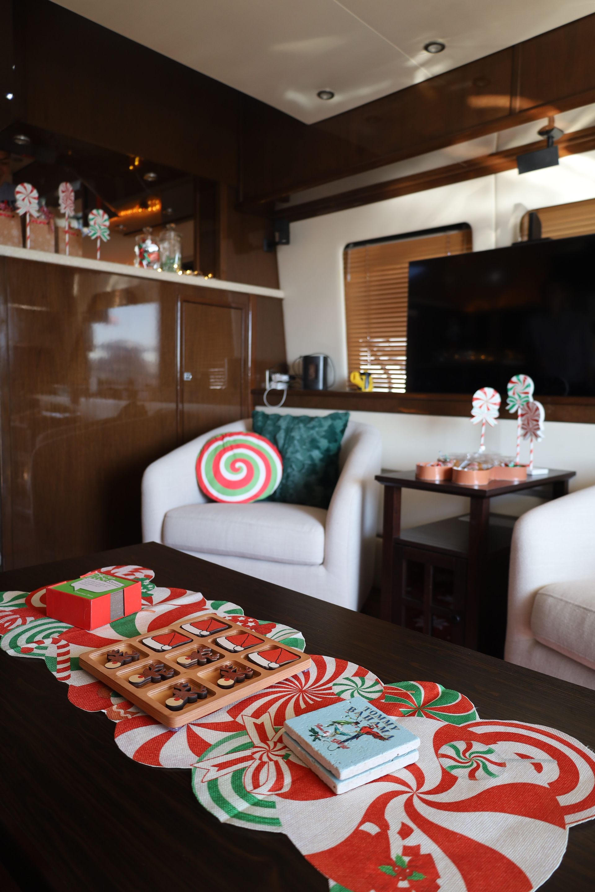 Living room with Christmas decorations: white chairs, coffee table with candy-themed runner, sweets, and gingerbread house decor.