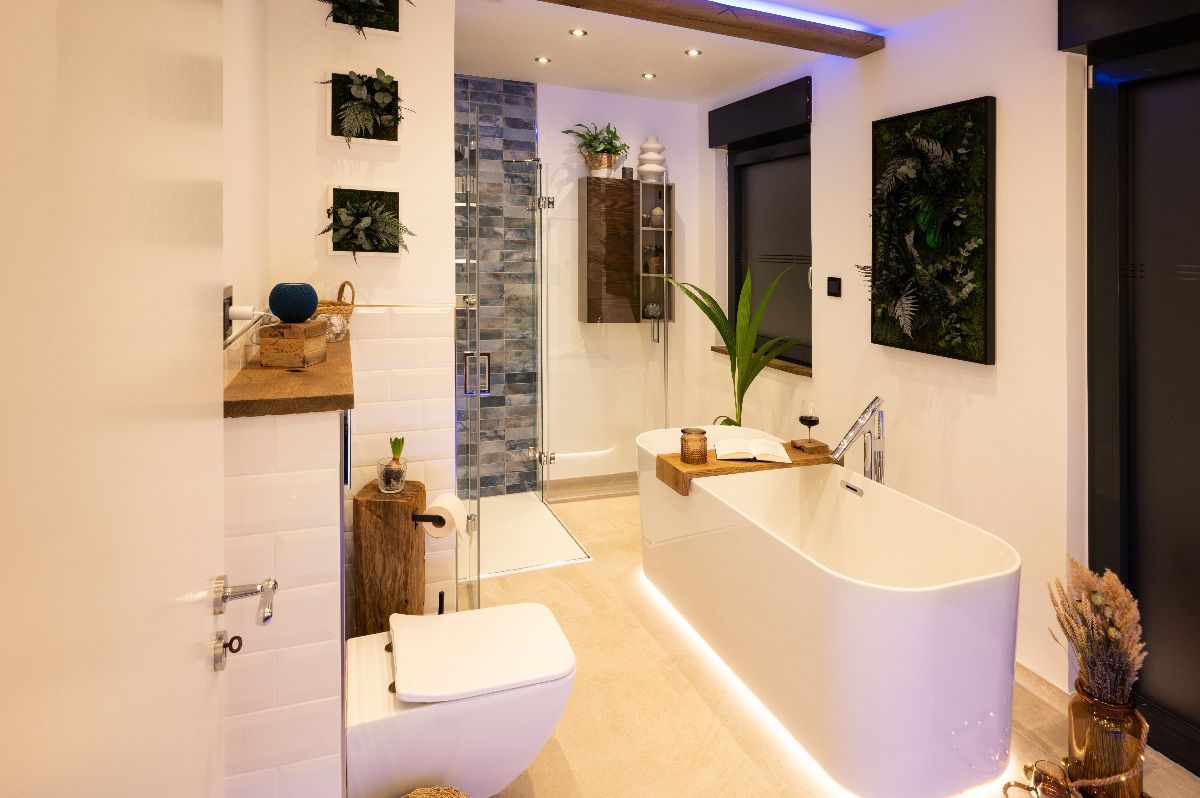Modern bathroom with freestanding tub, plants, and blue accent wall.