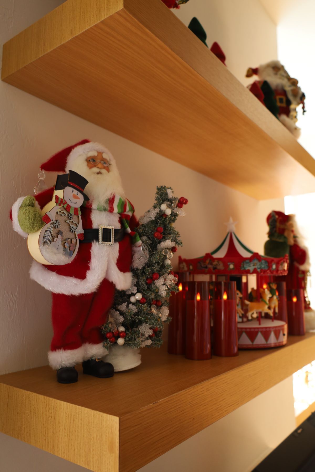 Christmas shelf decorations with Santa Claus, snowman, tree, carousel, and candles.