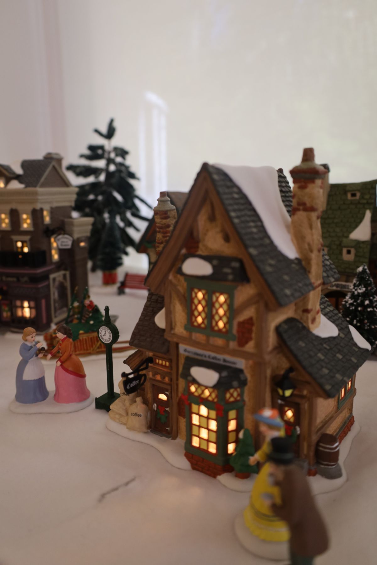 Christmas village scene with illuminated buildings, snowy rooftops, and figurines.