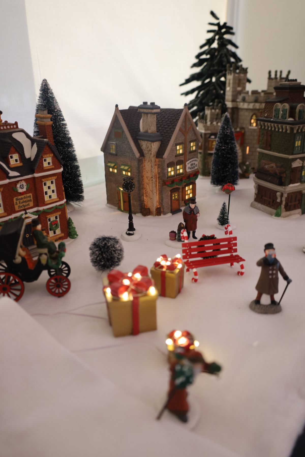 Christmas village scene with lit houses, snow, presents, and figures.