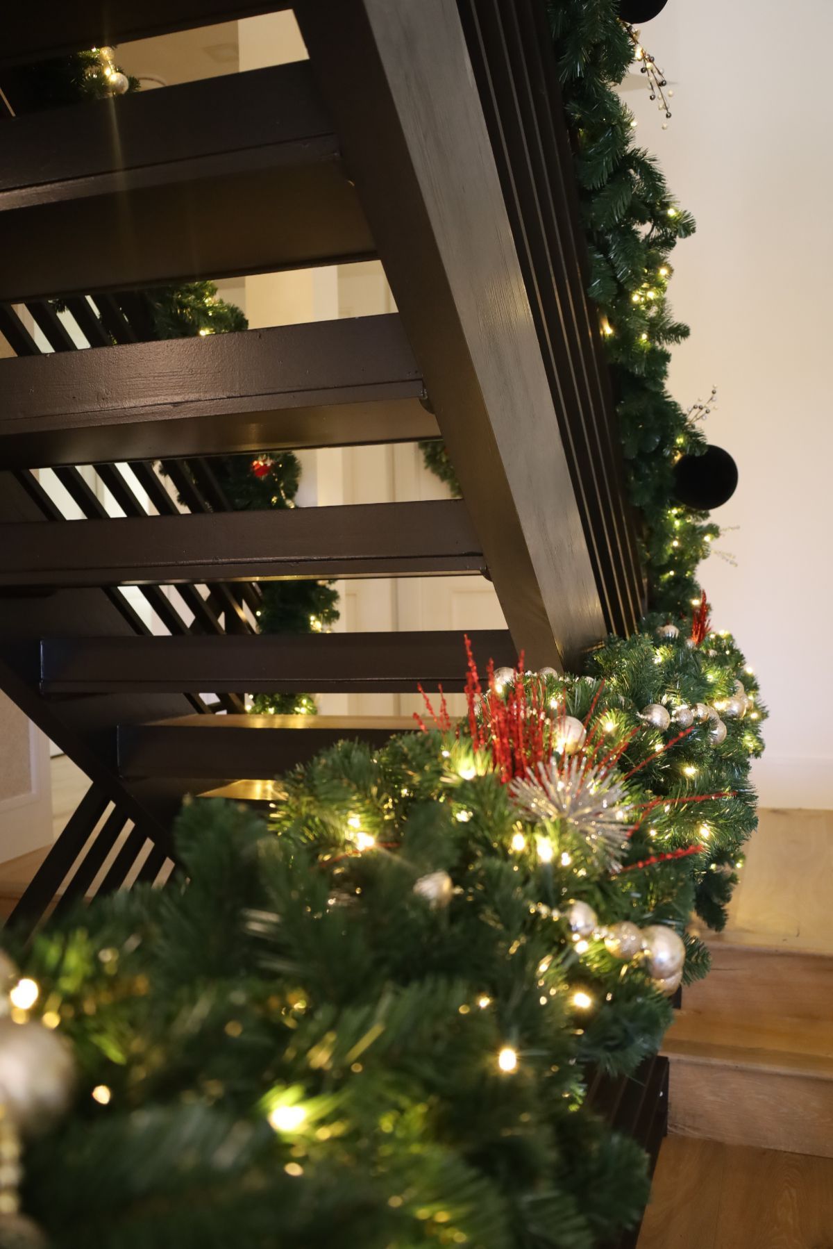 Staircase decorated with green garland, fairy lights, and ornaments for Christmas.