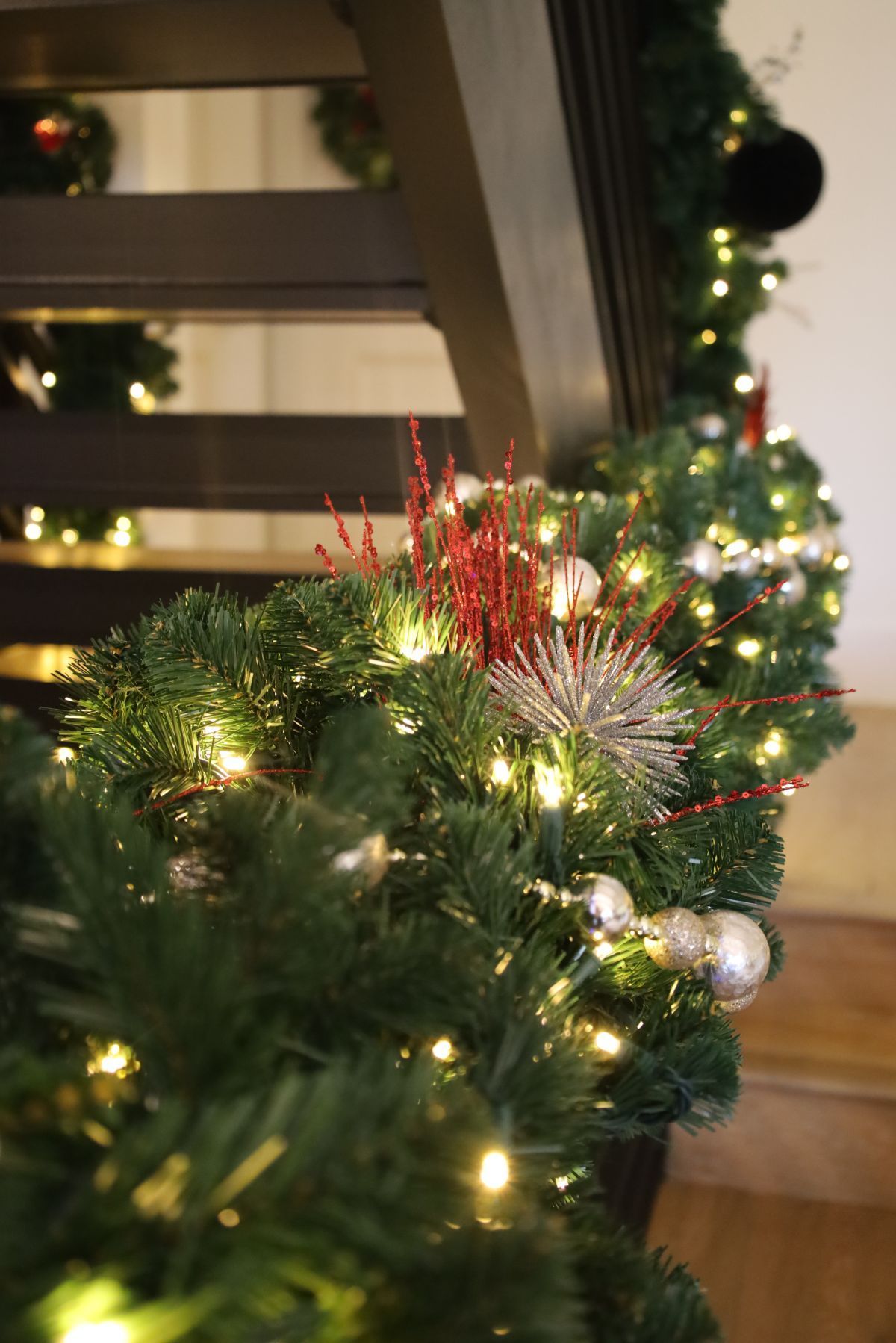 Christmas garland draped along a staircase banister, decorated with lights and ornaments.