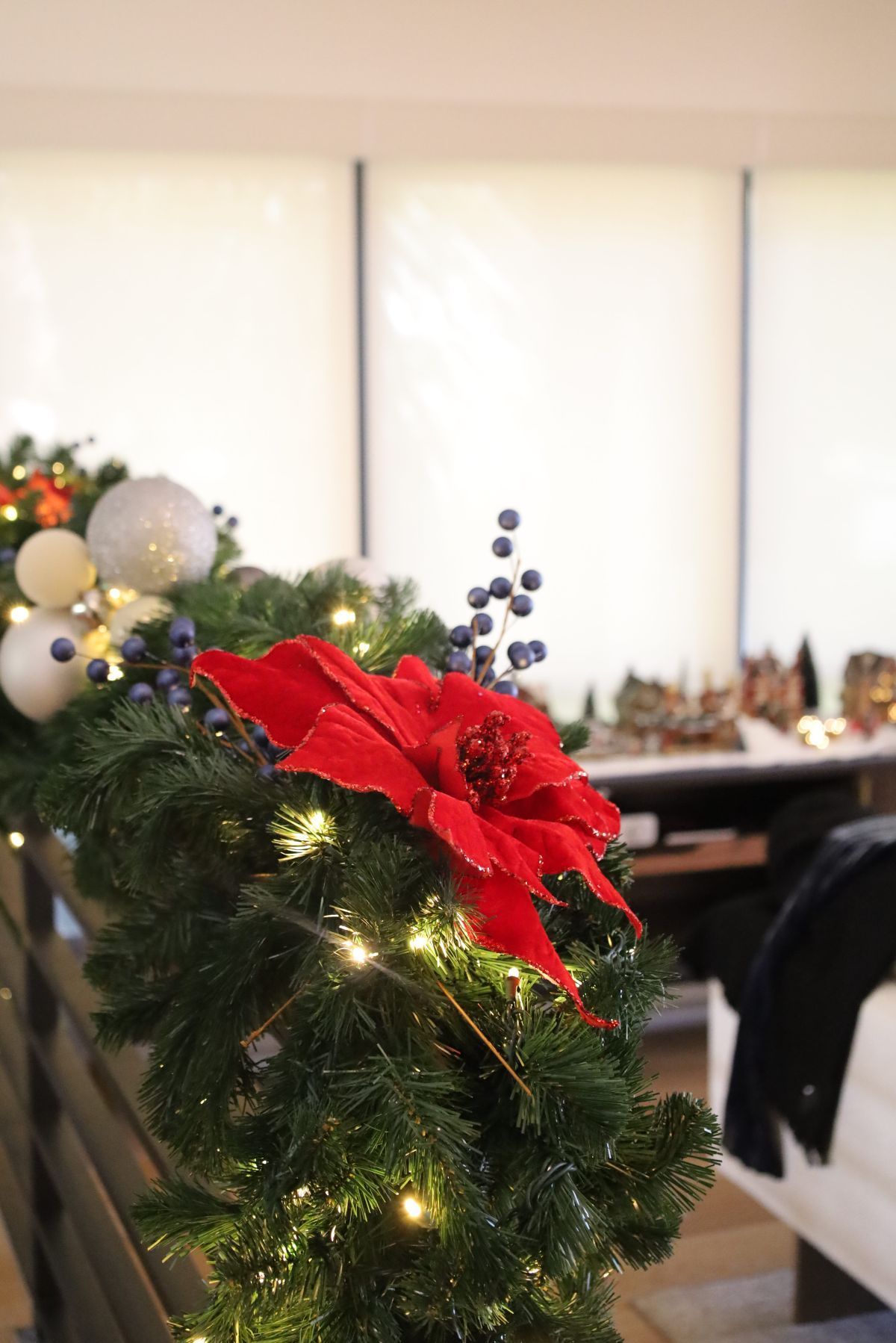 Christmas garland with red poinsettia and lights, draped on a railing.