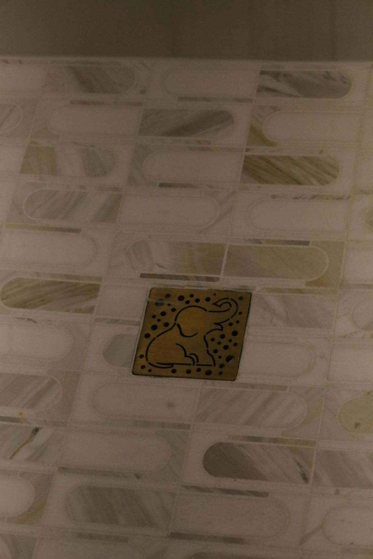 Wooden elephant mosaic tile on marble patterned wall.