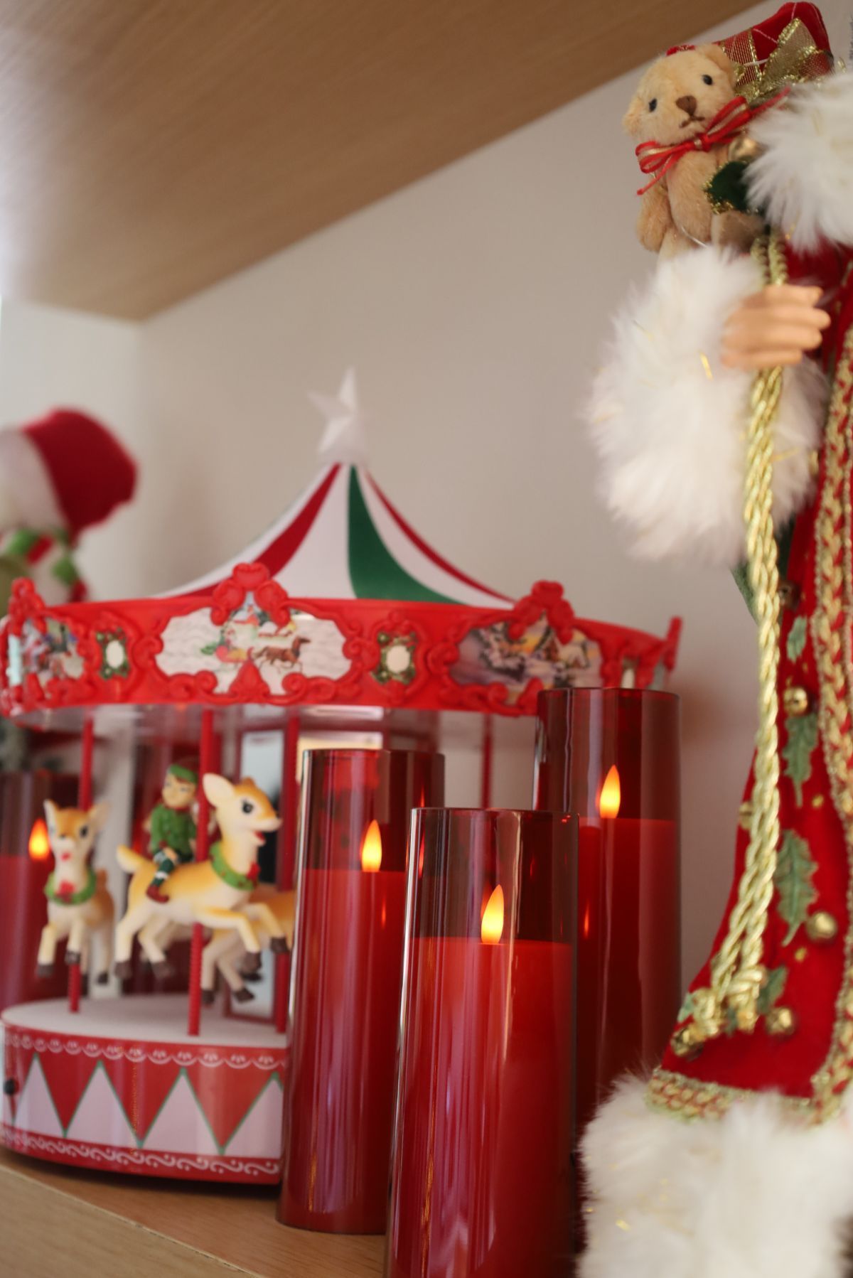 Christmas mantel display with carousel, candles, and Santa figurine.
