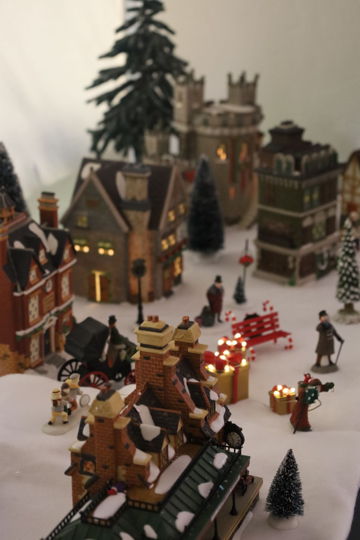 Christmas village scene with snow-covered buildings, trees, and tiny figures.