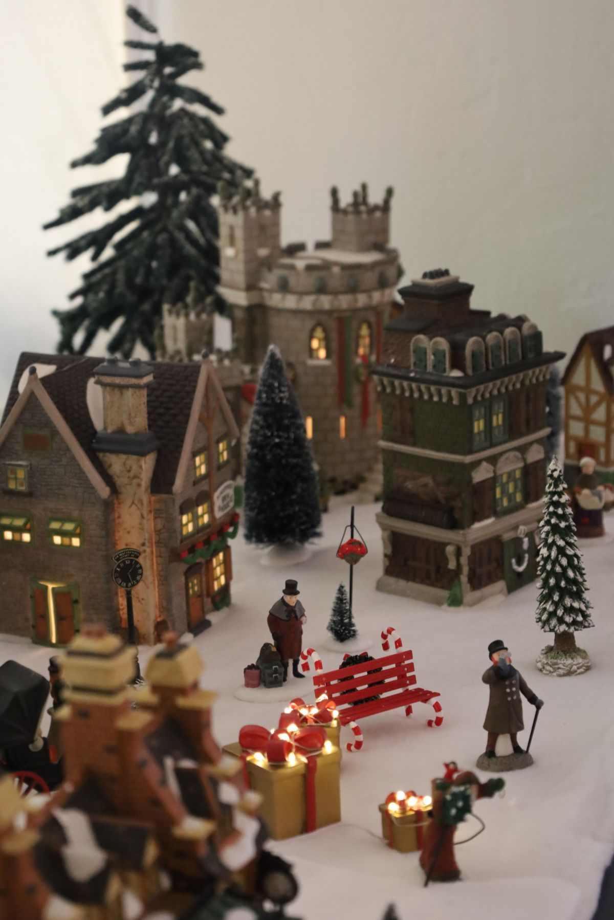 Miniature Christmas village display with buildings, figures, lights, and snow.