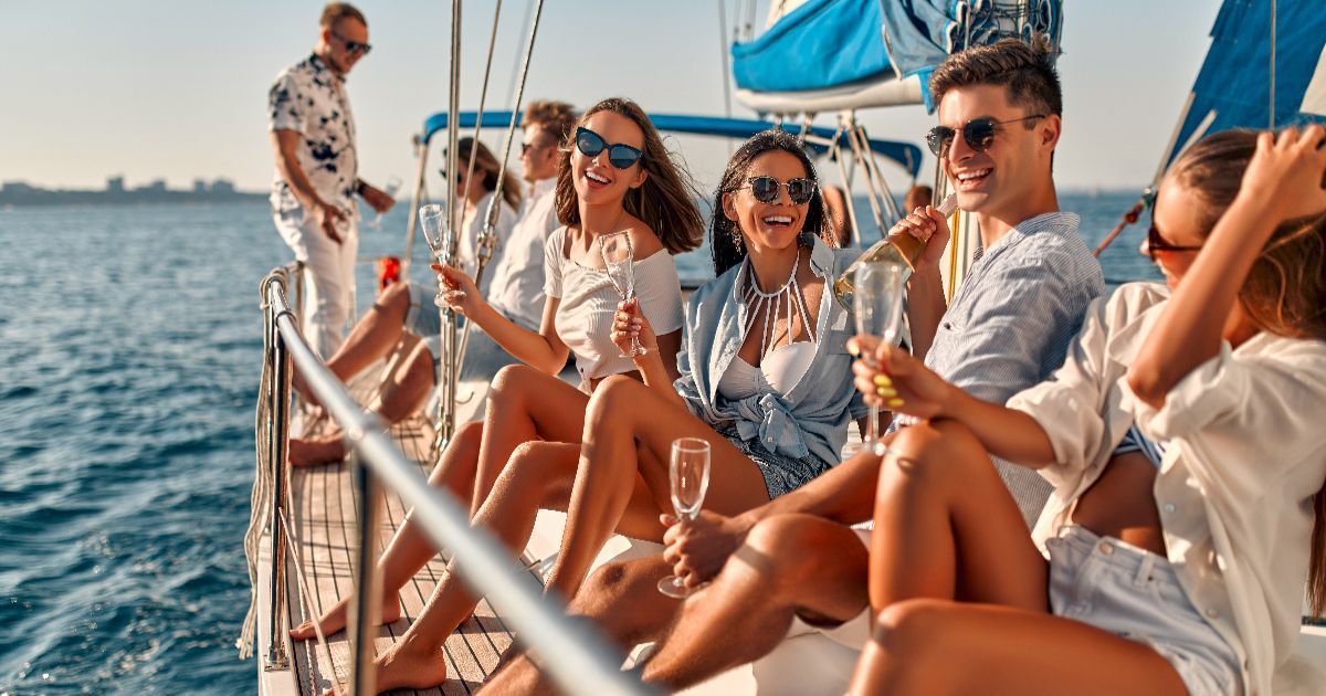 People on a sailboat, enjoying drinks in the sun. Ocean setting.